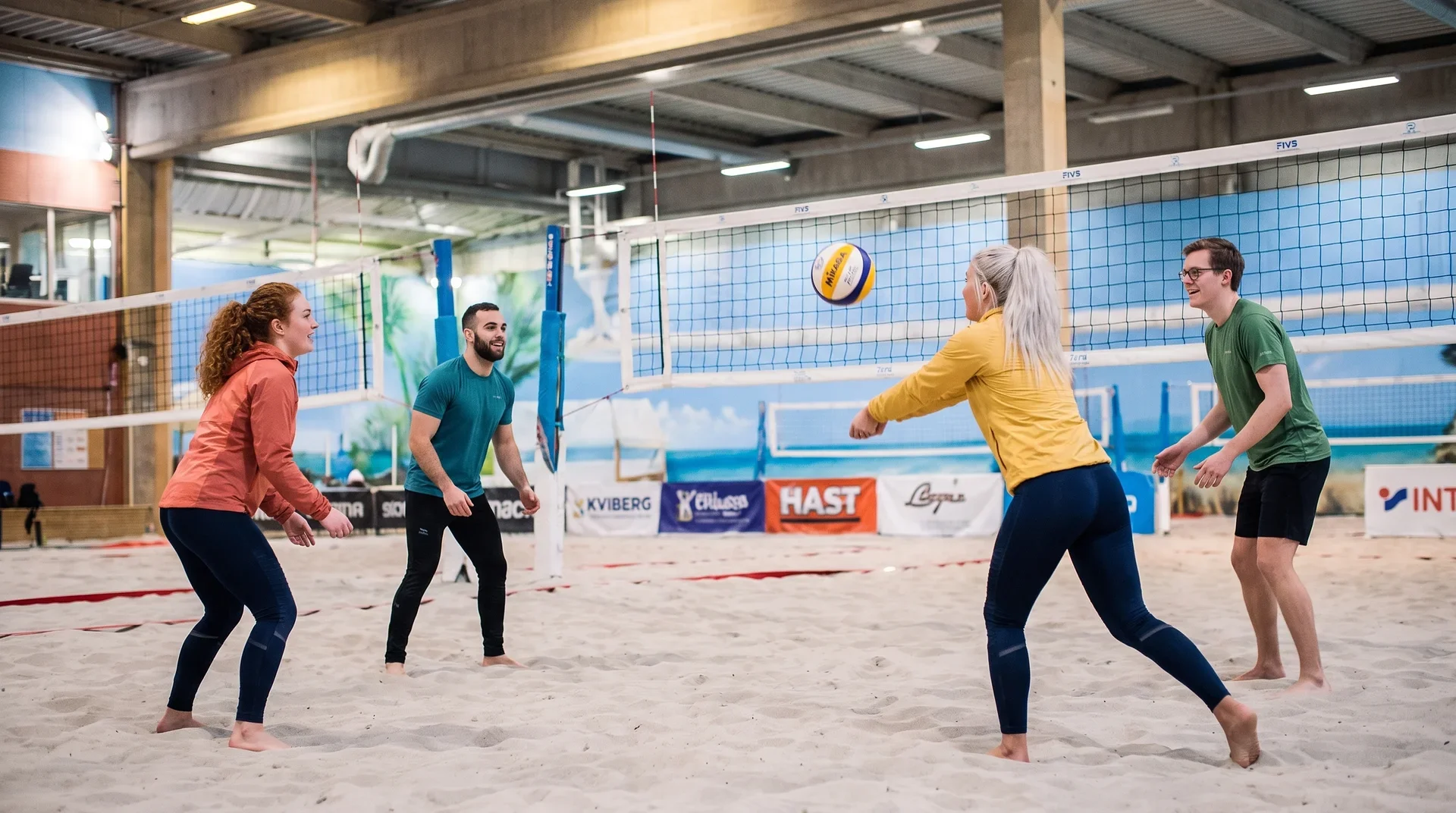 Fyra vänner spelar beachvolley i inomhushallen på Kviberg Beach Center.