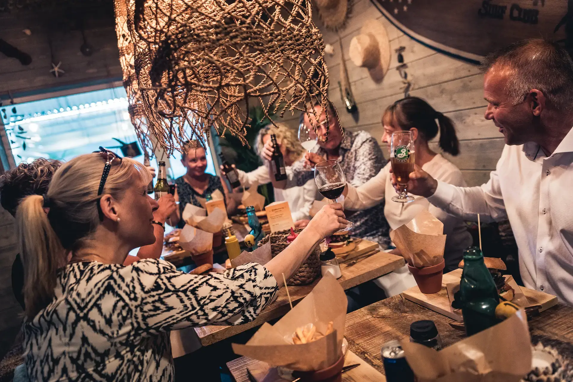En grupp människor skålar med öl och vin på en restaurang.